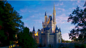 Disney Cruise Line NY Sailings Bahamian Cruises - A shoreline pressed up against a grassy hill with buildings and trees Cinderella Castle framed between trees against a twilight sky