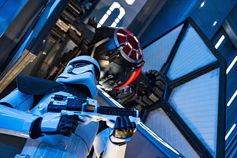 A First Order Stormtrooper stands guard in a Star Destroyer hangar bay beneath a docked TIE fighter in Star Wars: Rise of the Resistance, the groundbreaking new attraction opening Dec. 5, 2019, inside Star Wars: Galaxy’s Edge at Disney’s Hollywood Studios in Florida and Jan. 17, 2020, at Disneyland Park in California. Guests enter the hangar bay after their ship is caught in the Star Destroyer’s tractor beam.